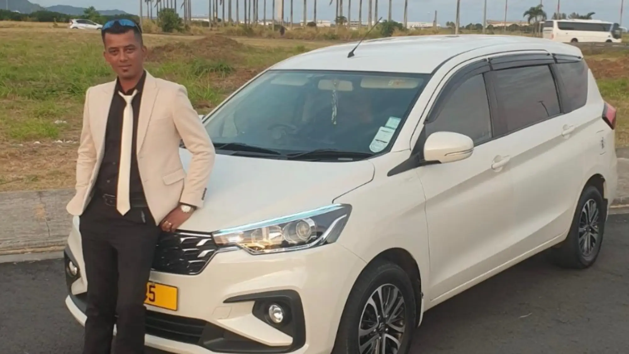 Professional driver beside a white SUV at Mauritius airport ready for transfer service